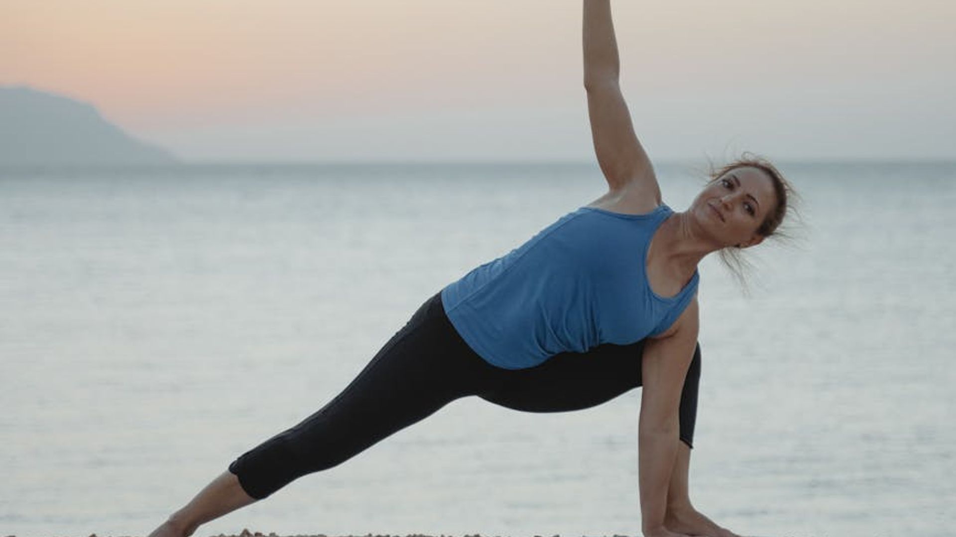 Person doing yoga in a dark room with violet lights.